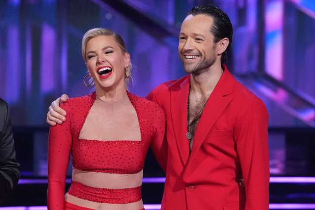 Ariana Madix and Pasha Pashkov smiling in matching red outfits on the dance floor.