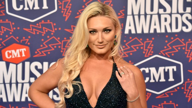 Brooke Hogan on the red carpet wearing a black dress with a deep neck plunge