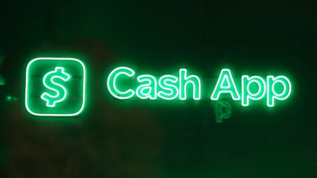 A neon green backlit sign displaying the name Cash App alongside its logo.