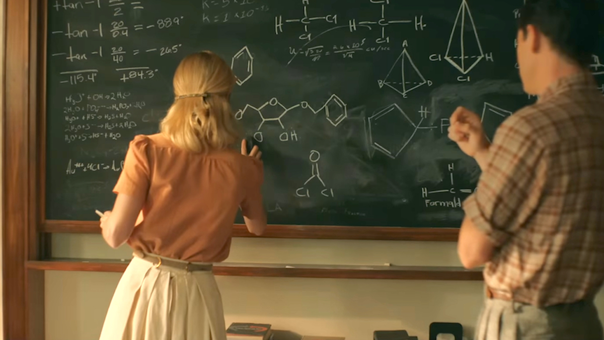 Brie Larson and Lewis Pullman as Elizabeth Zott and Calvin Evans standing at a chalkboard full of chemistry diagrams in Apple TV Plus' 'Lessons in Chemistry'