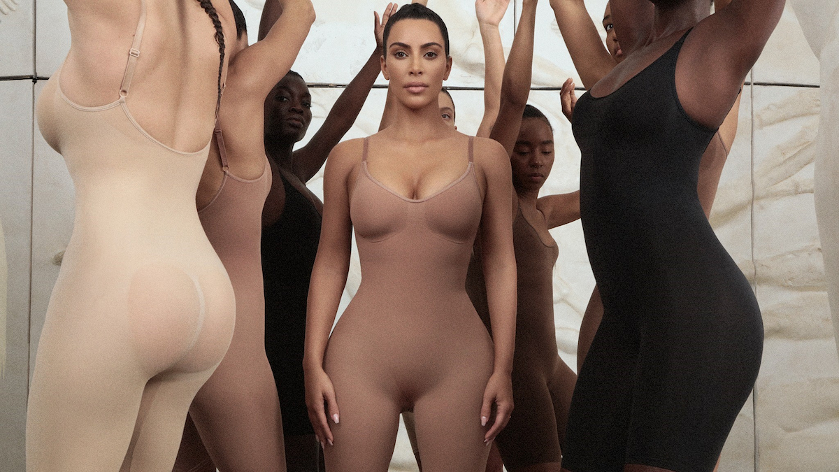 Kim Kardashian posa em shapewear com modelos ao seu redor. 