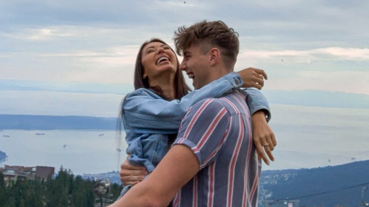 Francesca Farago and Harry Jowsey embrace while laughing, with the LA skyline behind them. 