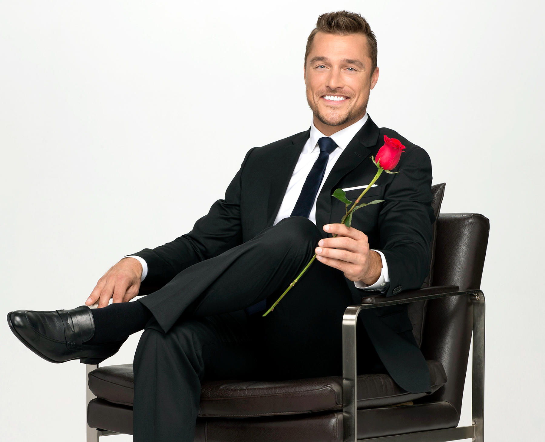 Chris Soules is sitting on a chair with a rose in his hand. 