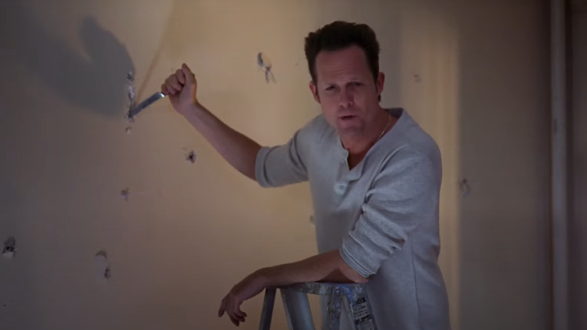 Dean Winters as Dennis Duffy, stabbing holes in a wall. 
