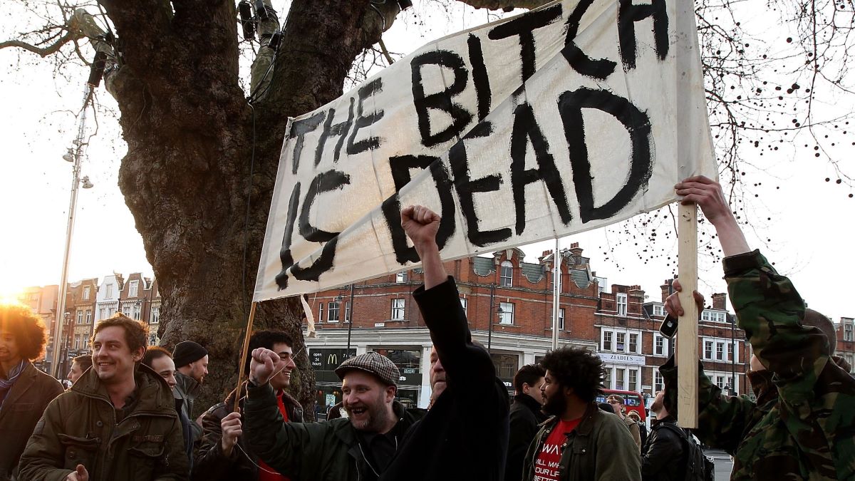 People hold banenrs and signs aloft as they celebrate the death of former British Prime Minister Margaret Thatcher following the announcement of her death in Brixton on April 8, 2013 in London, England. Lady Thatcher has died this morning following a stroke aged 87. Margaret Thatcher was the first female British Prime Minster and governed the UK from 1979 to 1990. She led the UK through some turbulent years and contentious issues including the Falklands War, the miners' strike and the Poll Tax riots. (Photo by Danny E. Martindale/Getty Images)