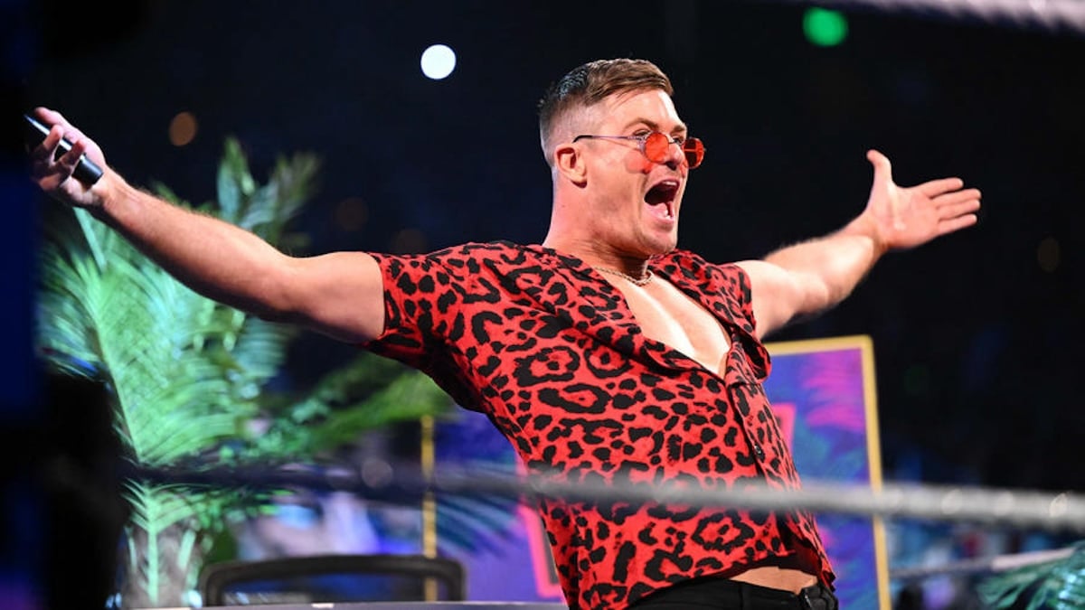 Grayson Waller shouting excitedly in the wrestling ring wearing a red cheetah print shirt and sunglasses