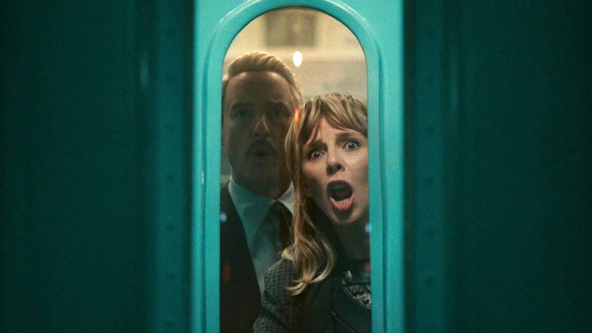 Mobius and Sylvie stare in shock through a door window in a screenshot from 'Loki' season 2