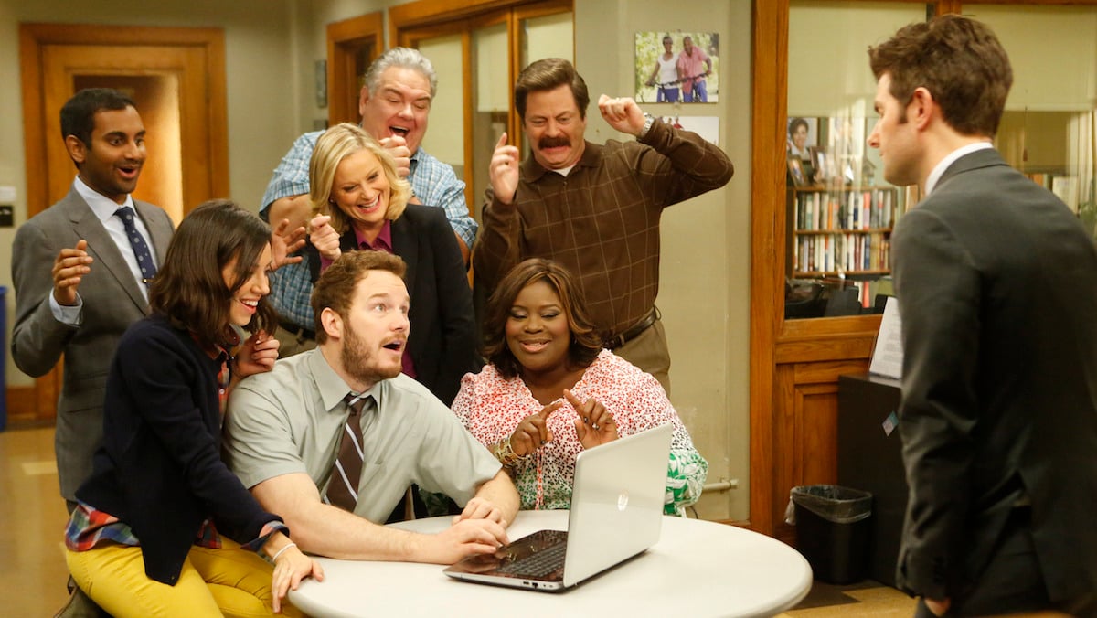 The Pawnee Parks and Recreation department cheer while looking at a laptop screen. 