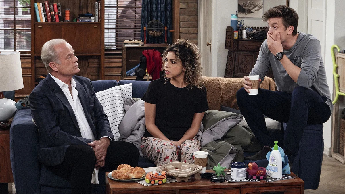 Frasier (Kelsey Grammer) sits on the sofa with Freddy (Jack Cutmore-Scott) and Eve (Jess Sagueiro). 