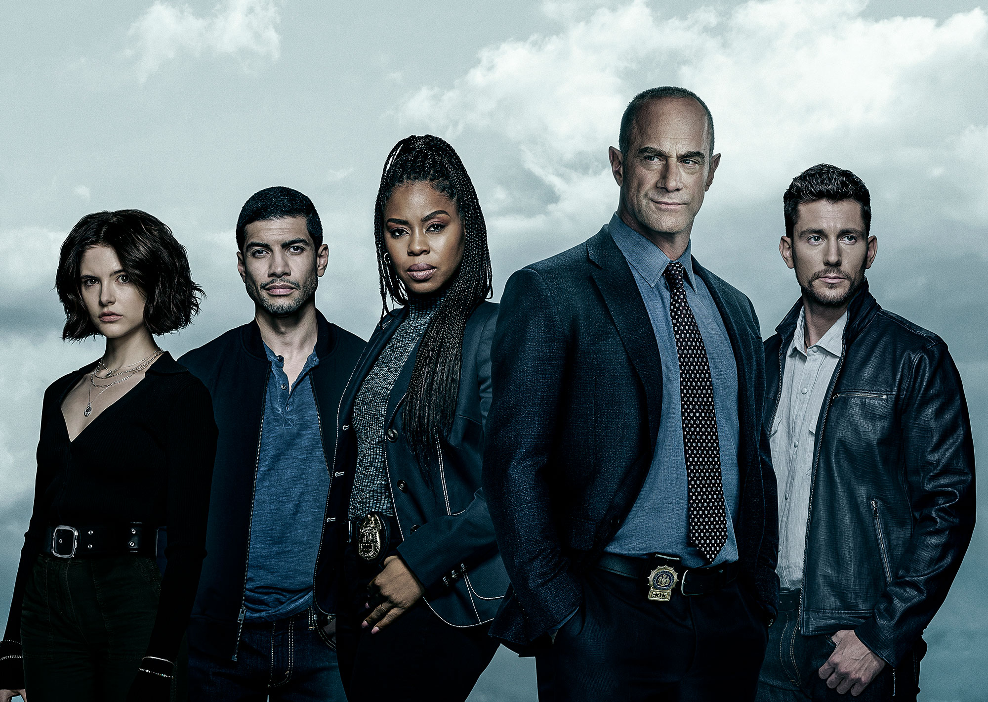 The cast of Law & Order: Organized Crime stands in front of clouds. 