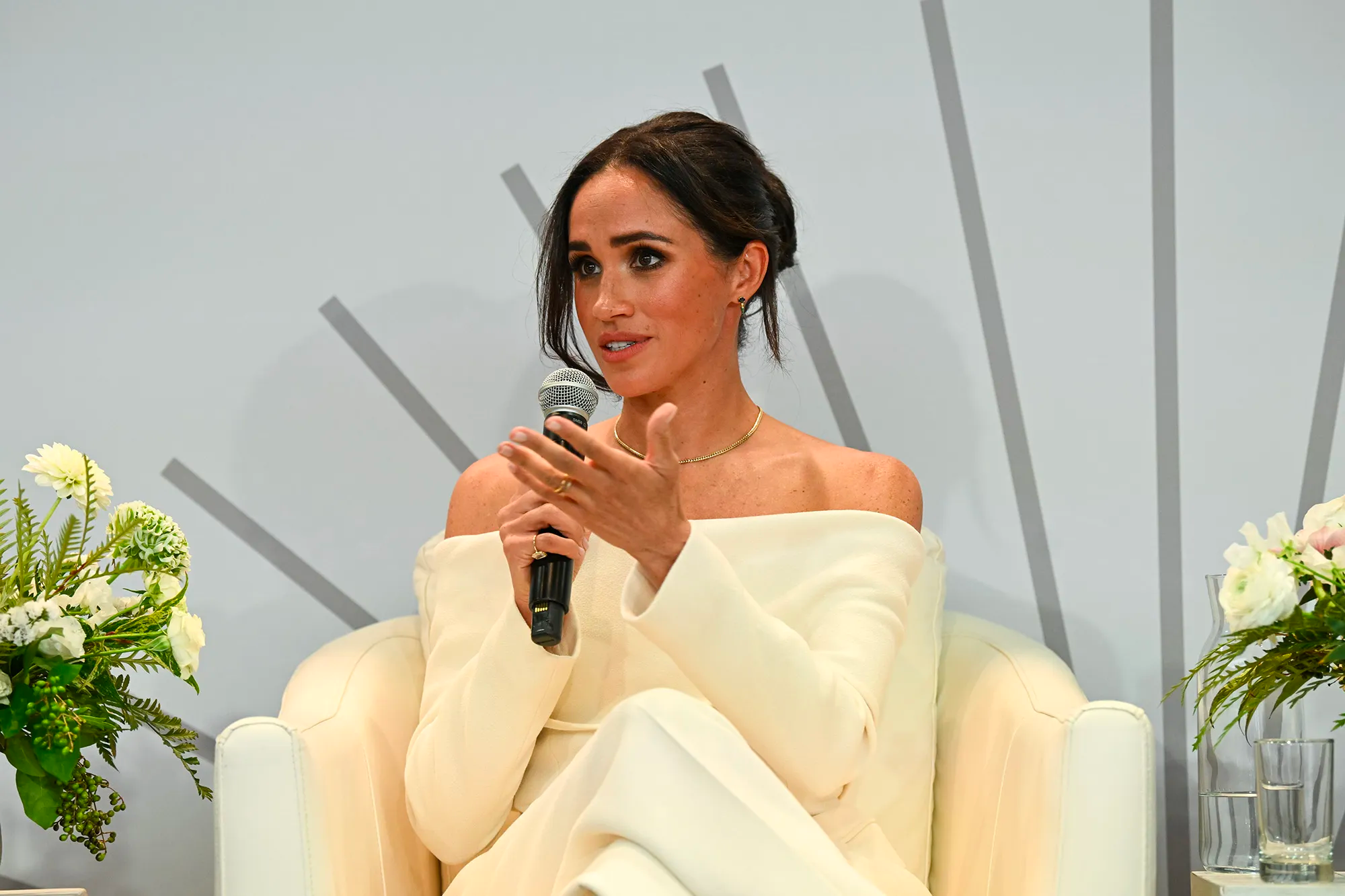 Meghan Markle is sitting and talking into a microphone.