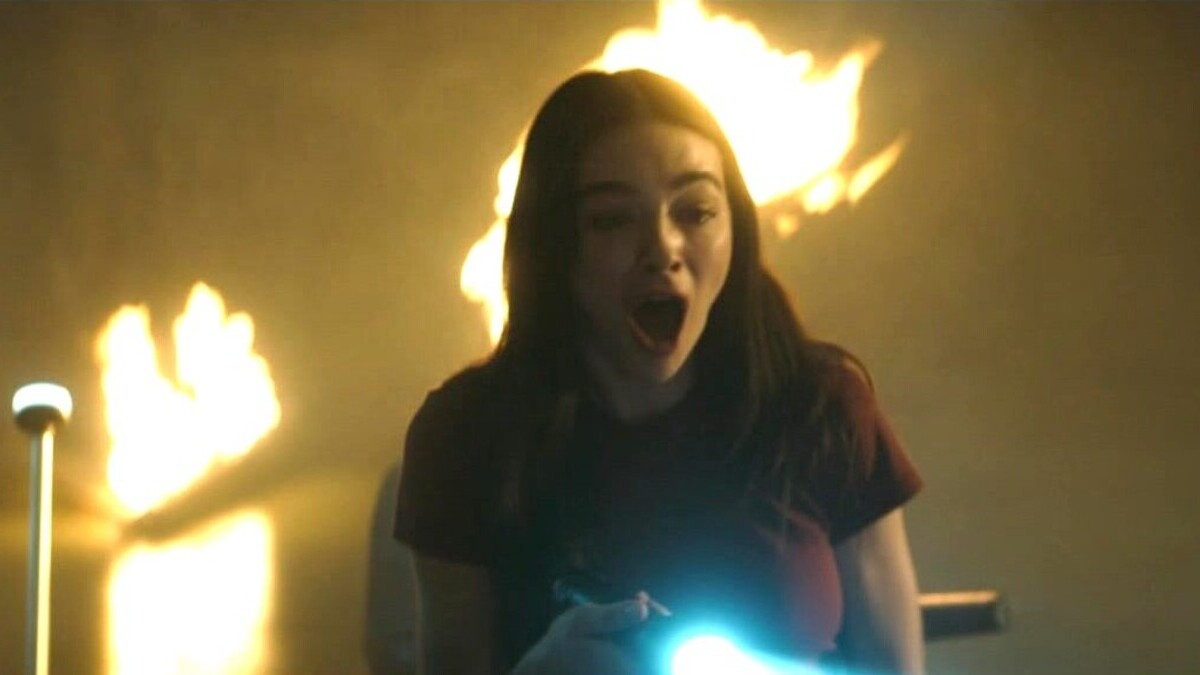 Abby Arcane (Crystal Reed) screams at the sight of something off screen as a fire blazes behind her in 'Swamp Thing' episode 1