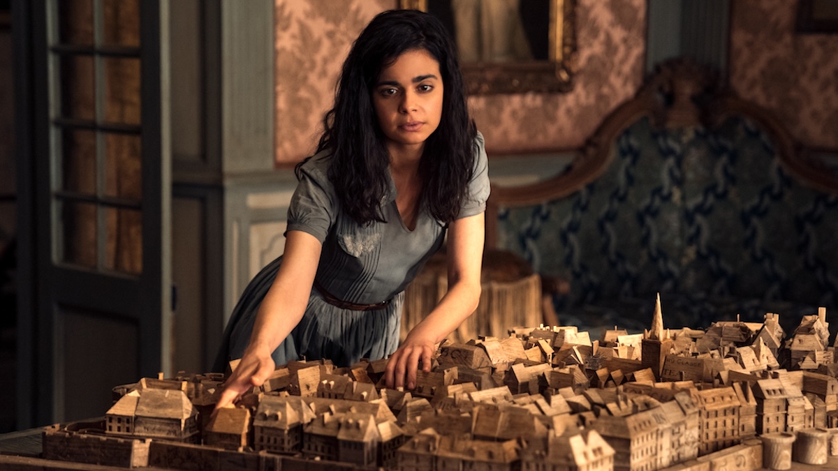 Image of Aria Mia Loberti's character Marie-Laure leaning over a miniature model of the city of Saint-Malo in Netflix's 'All the Light We Cannot See'