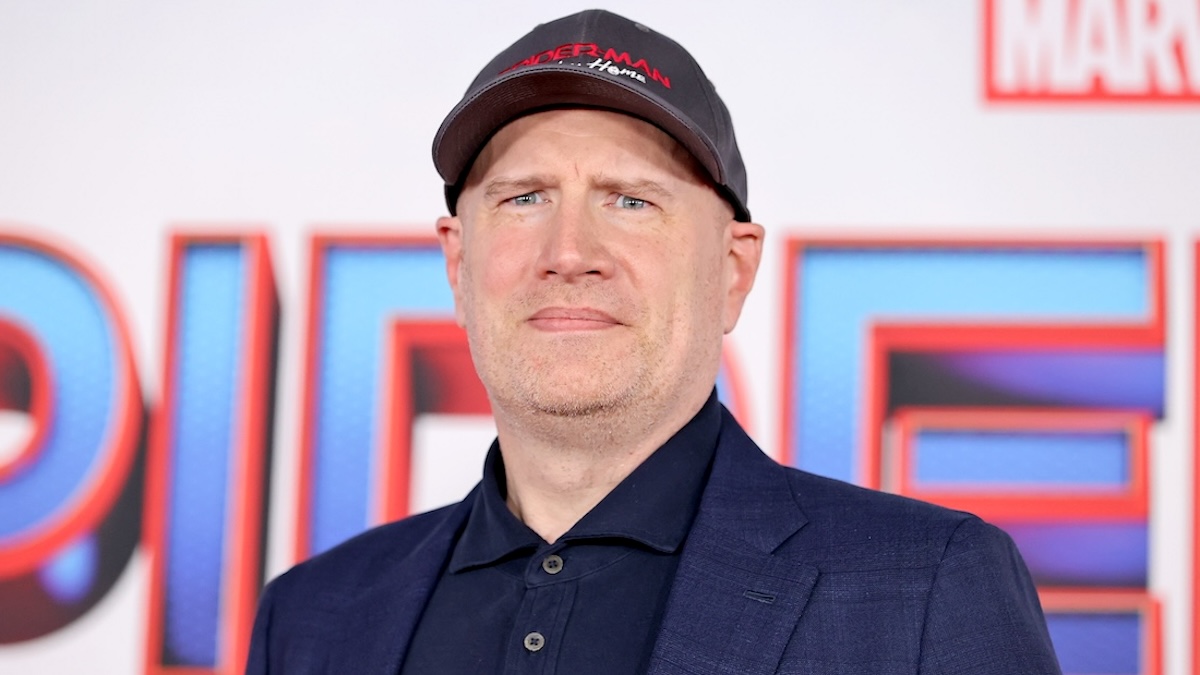A photo of Marvel Studios president Kevin Feige wearing a black 'Spider-Man' hat and standing on the red carpet with the cut-off letters of 'Spider-Man' on the backdrop behind him