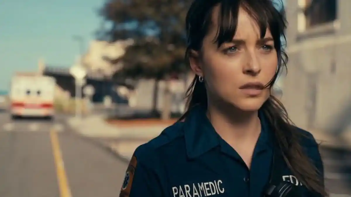 Cassandra Webb (Dakota Johnson) in her paramedic uniform stands by an ambulance in Madame Web