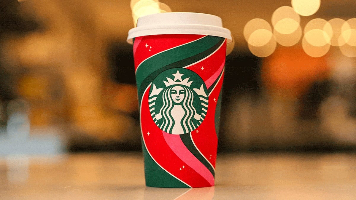 A solo Starbucks holiday cup with swirls of green and red ribbon wrapped around the Starbucks logo