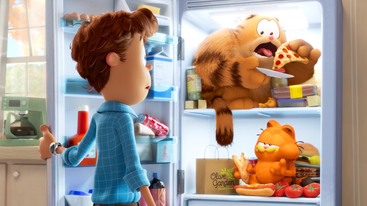 Jon opening the fridge to find Vic and Garfield eating pizza and hot dogs inside in 2024's 'The Garfield Movie'