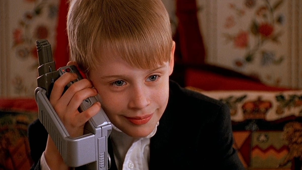 Kevin McCallister listens to his TalkBoy while sitting on his parents' bed in Home Alone 2: Lost in New York
