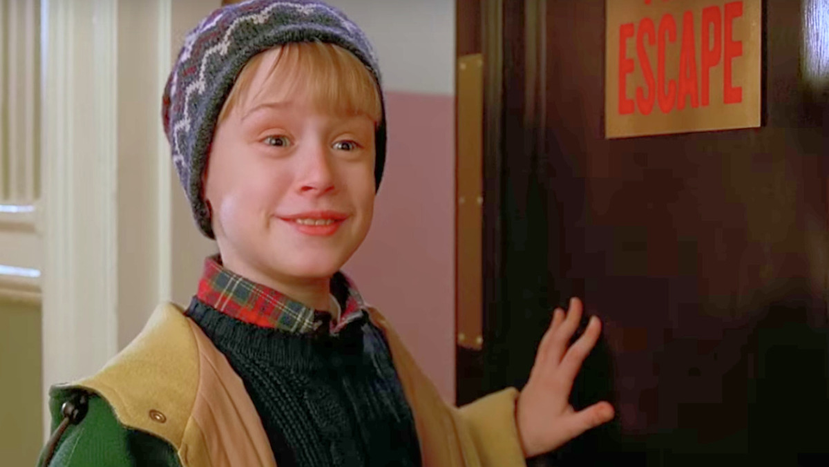 Kevin McCallister smirks as he opens a fire escape door in the Plaza Hotel in Home Alone 2: Lost in New York