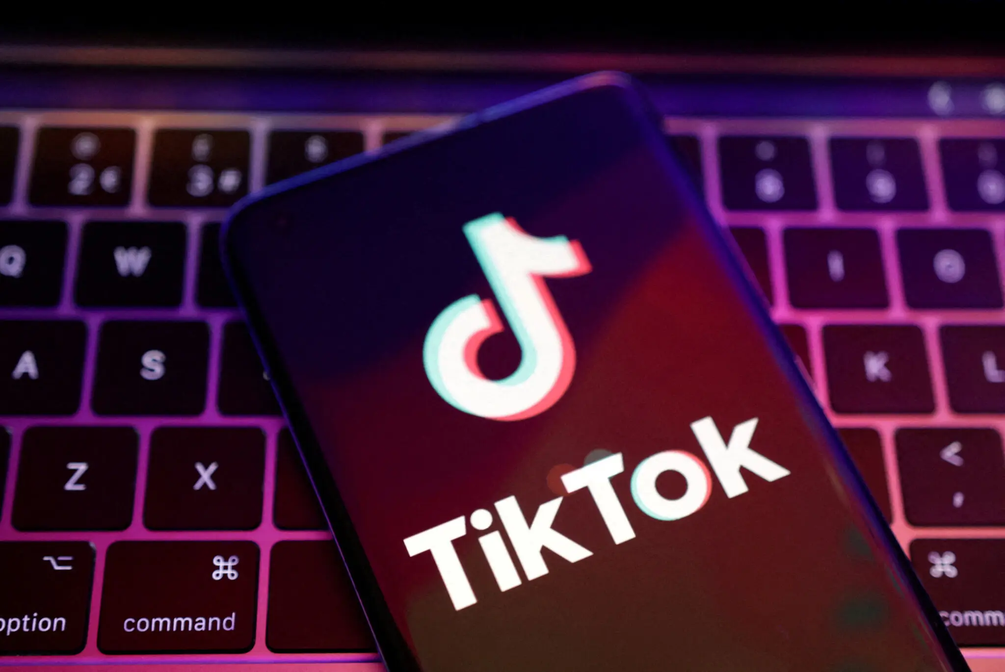 A phone with TikTok open is on a laptop.