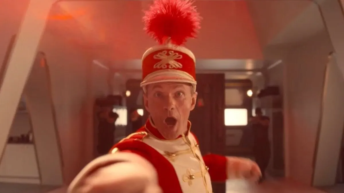 Neil Patrick Harris in a marching band outfit pulls a shocked face at the camera in a still from Doctor Who special The Giggle.