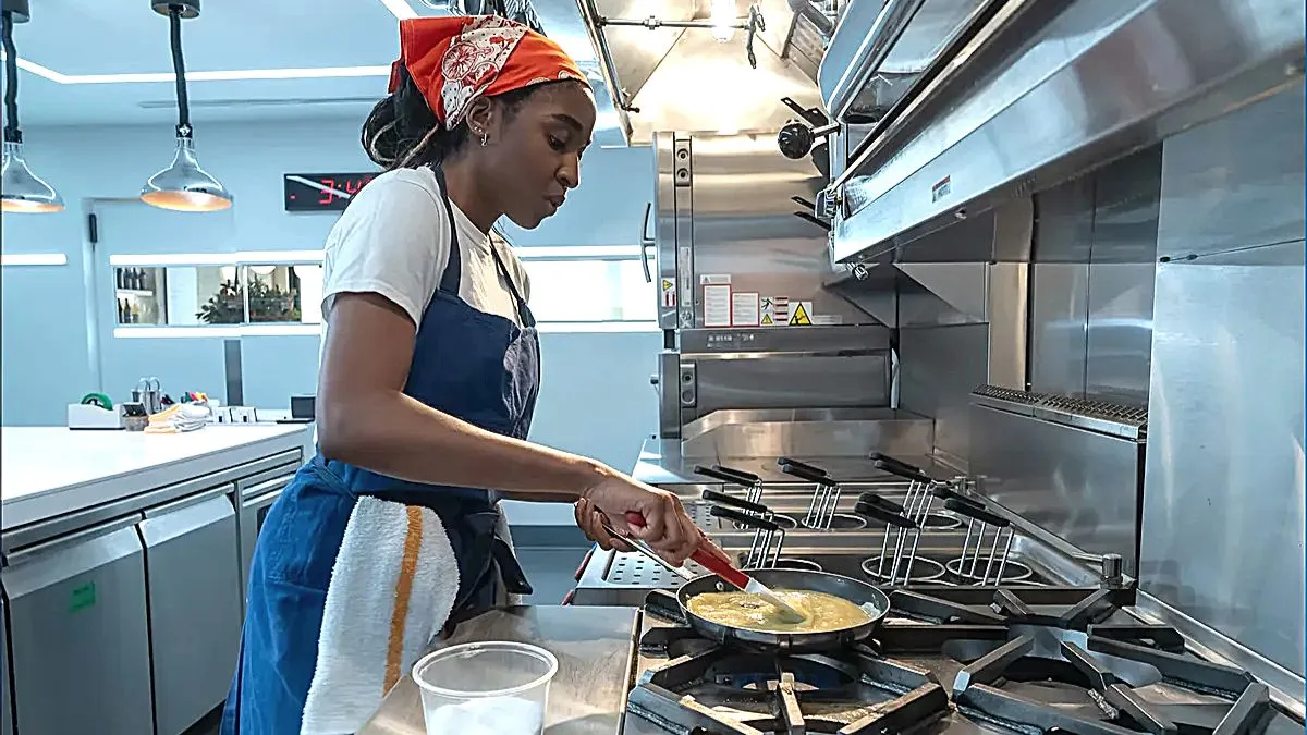 Imagem estática da 2ª temporada de 'The Bear', onde Ayo Edebiri cozinha a omelete perfeita como sua personagem Sydney.