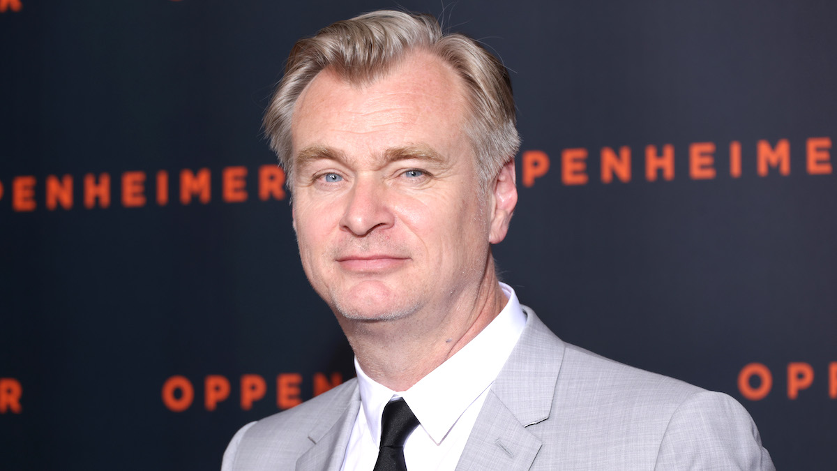 Christopher Nolan wears a light gray suit and a black tie at the 'Oppenheimer' premiere at Cinema Le Grand Rex in 2023.
