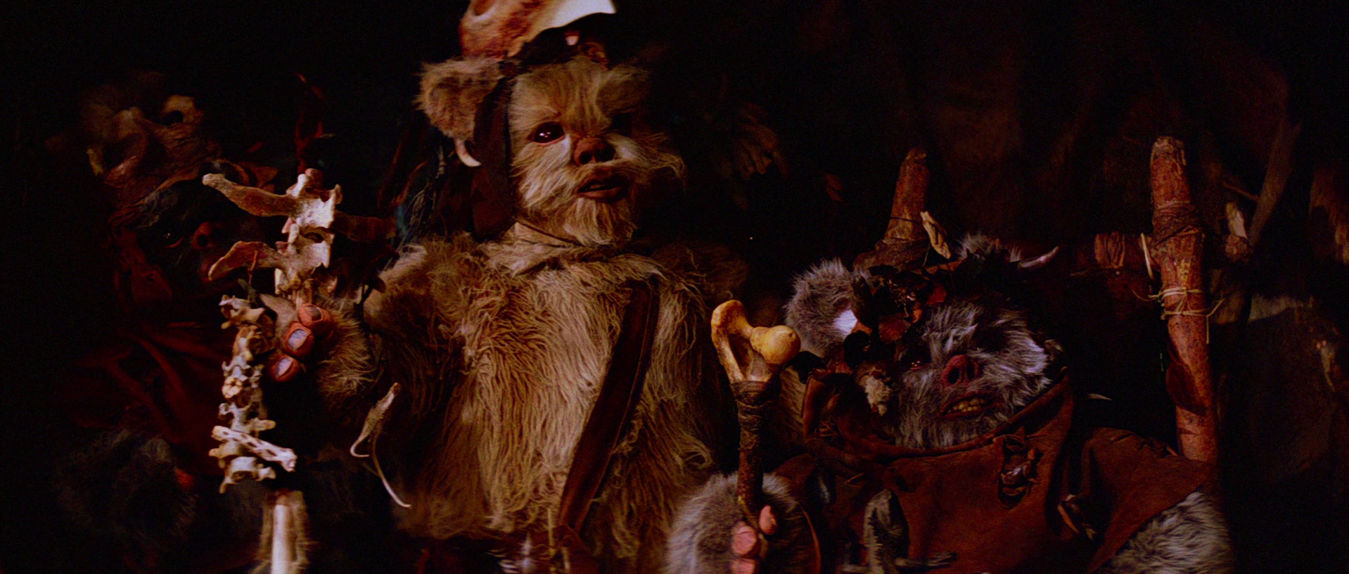 A Chripa Ewok is holding a sticks in his hands.
