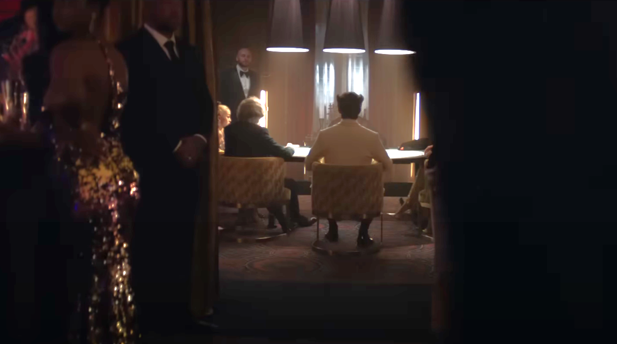 From behind, Wolverine in a white suit plays cards at a private table