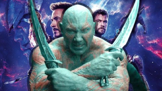 Dave Bautista wields twin blades as Drax superimposed over the Avengers: Endgame poster