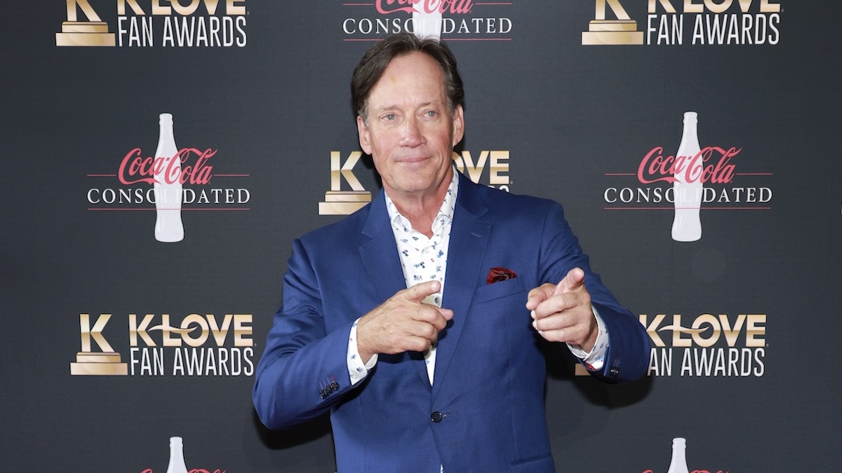 Kevin Sorbo pointing to someone off-camera in a navy blue suit