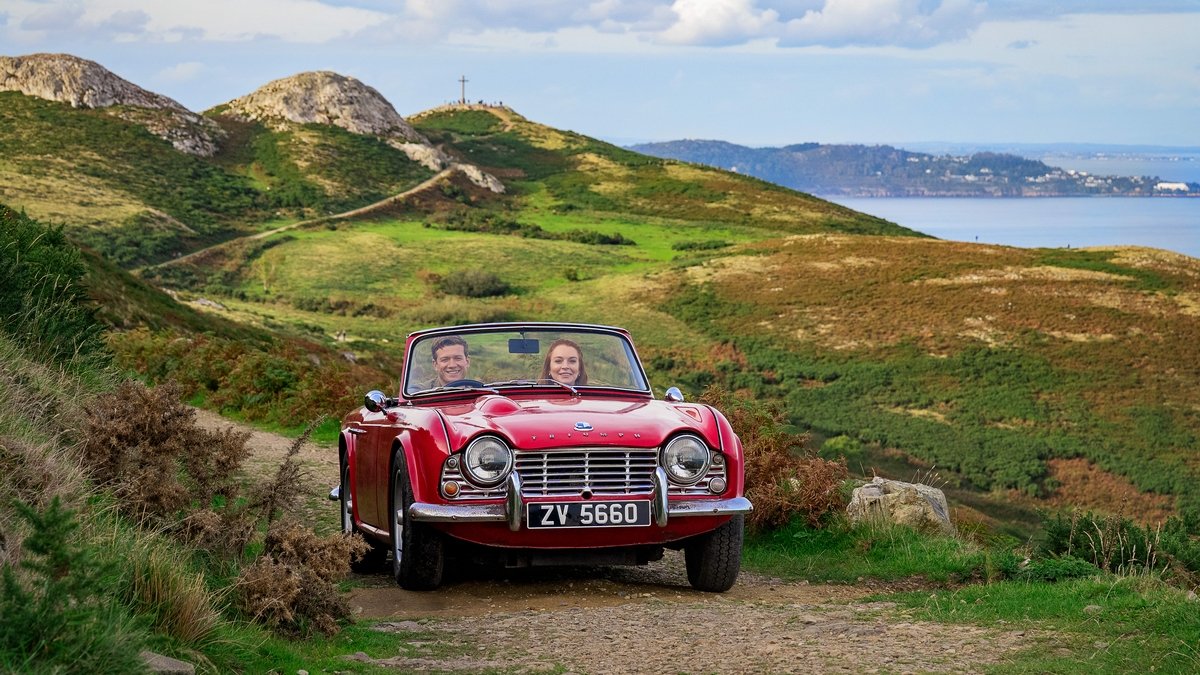 Ed Speleers and Lindsay Lohan driving through Ireland's countryside in the movie Irish Wish