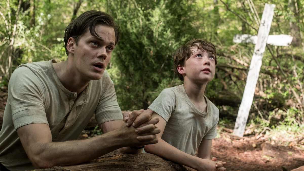 Bill Skarsgård and Willard Russell on their knees praying in the movie TheDevil All the Time