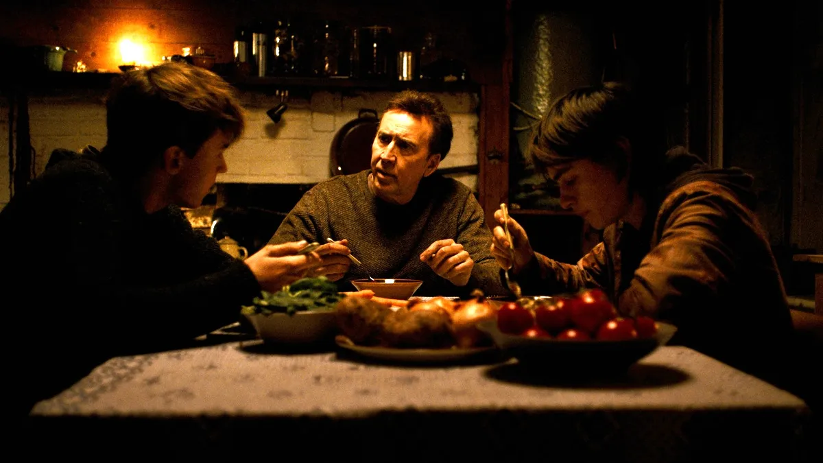 Nicolas Cage, Maxwell Jenkins, and Jaeden Martell having dinner in the horror movie Arcadian