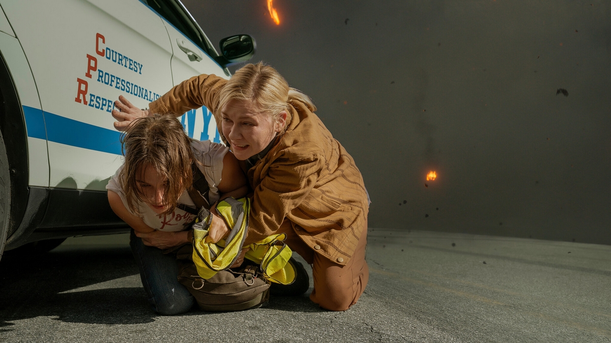 Kirsten Dunst keeping Cailee Spaeny down behind a car in Alex Garland's Civil War