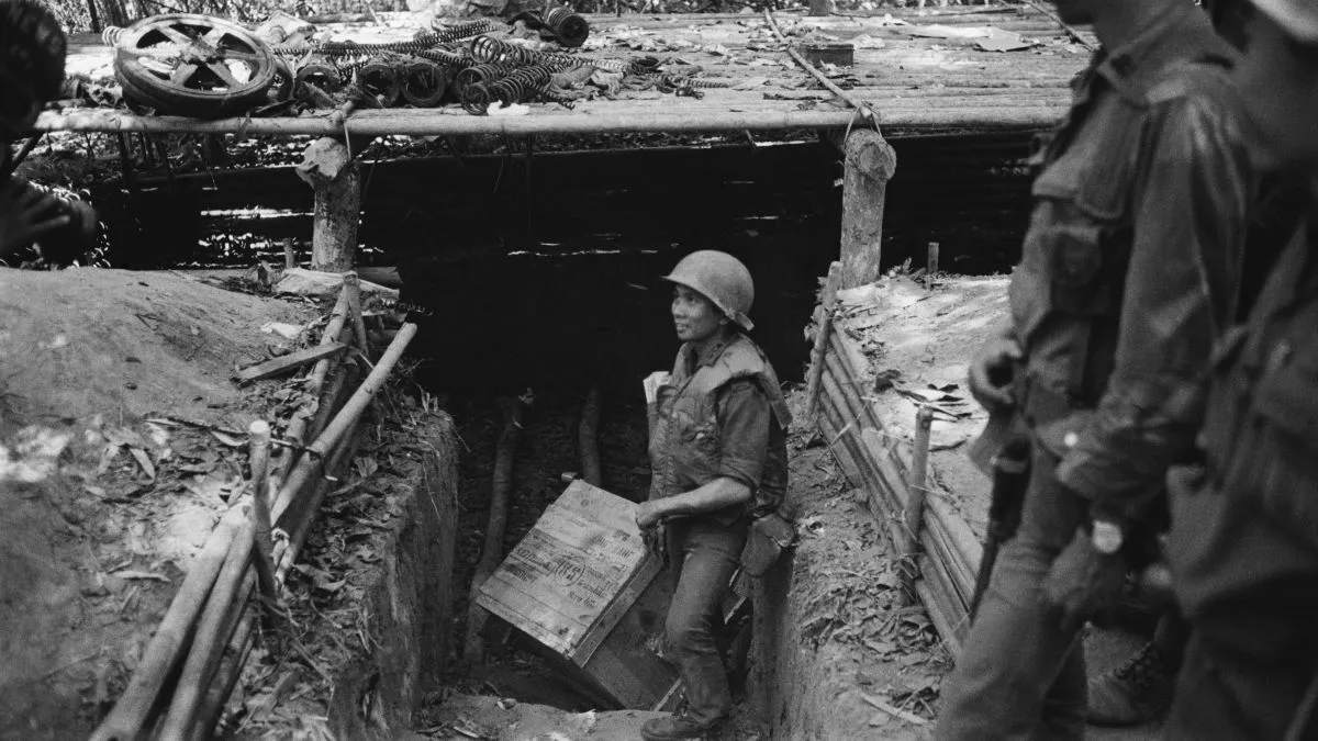 (Original Caption) 02/14/71- Ho Chi Minh Trail, Laos: An ARVN soldier hauls out some of the supplies from a bunker discovered on the Ho Chi Minh Trail. North Vietnamese used the bunkers as storage depots and protective cover. Caches of Gasoline, weapons and uniforms have been uncovered. UPI radiophoto by Bob Sullivan.
