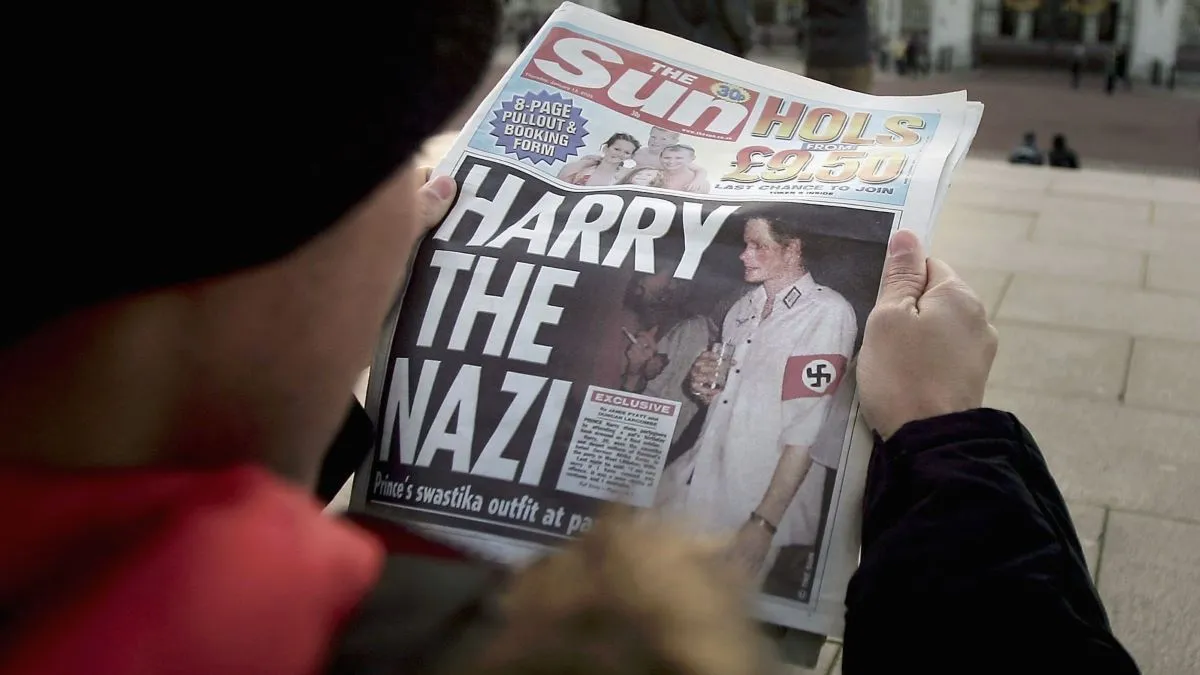 A man is seen reading a copy of The Sun newspaper in front of Buckingham Palace on January 13, 2005 in London, England. Prince Harry made the headlines again this morning with the news that he arrived at a friends birthday party dressed in Nazi outfit just a fortnight before the 60th anniversary of the liberation of Auschwitz. The Prince, who has been fiercely criticised for his actions, has apologised for his choice of costume. (Photo by Bruno Vincent/Getty Images)