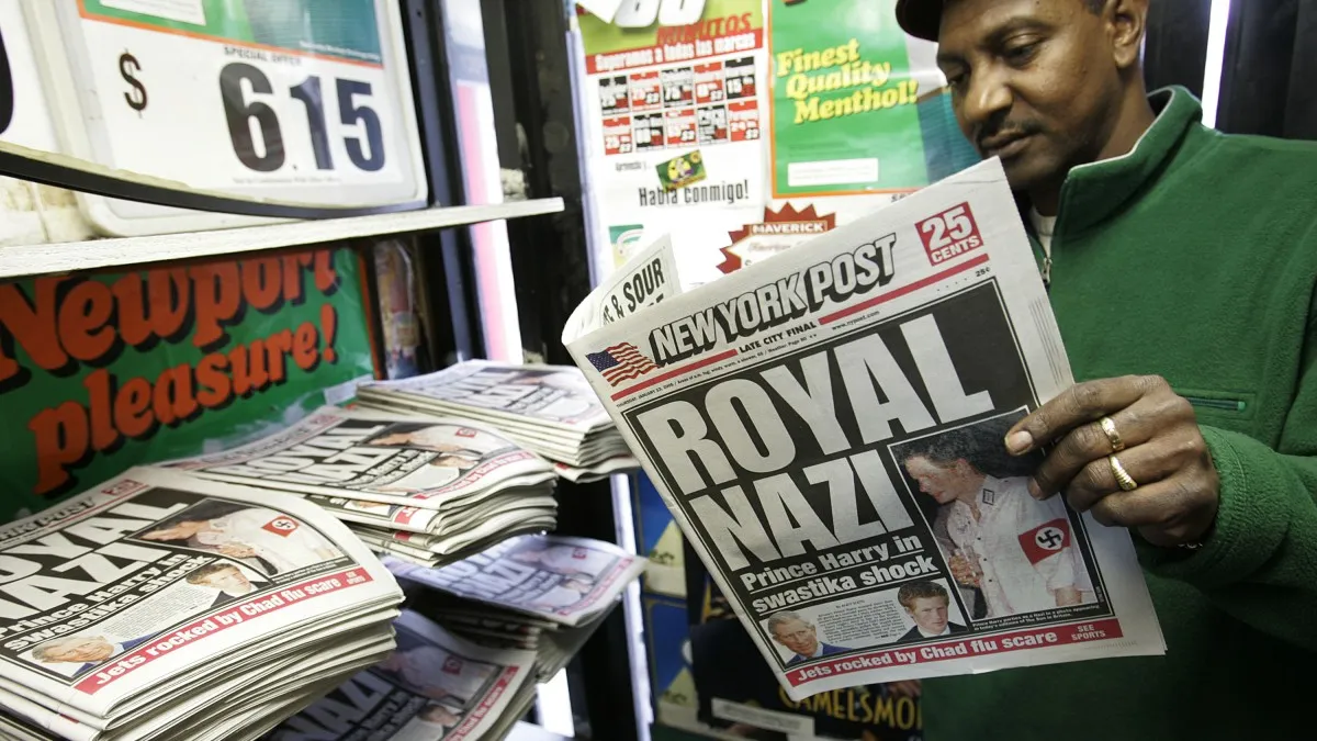 A man identified as Hussein reads a copy of the New York Post newspaper featuring a "Royal Nazi" headline January 13, 2005 in New York City. British royal, Prince Harry, reportedly attended a fancy dress party wearing a khaki uniform with an armband emblazoned with a swastika, the emblem of the German WWII Nazi Party. (Photo by Stephen Chernin/Getty Images)