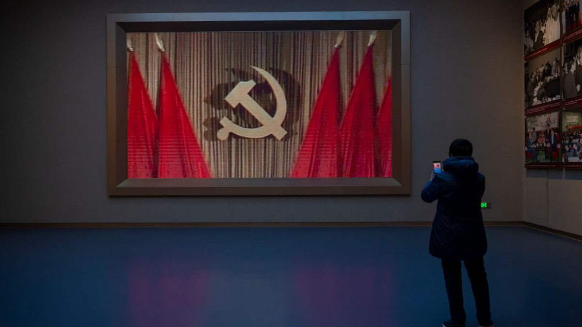A visitor takes a photo as a hammer and sickle sign is seen in a video played at the Museum of the Communist Party of China on December 16, 2021 in Beijing, China. The museum was officially opened in June 2021, the year the party celebrated the 100th anniversary of its funding. 