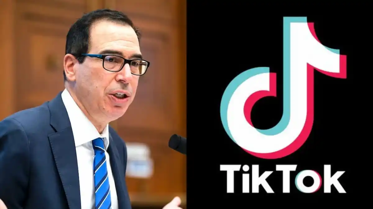 Steven Mnuchin wearing black glasses and a blue seat and speaking into a microphone at a 2020 hearing