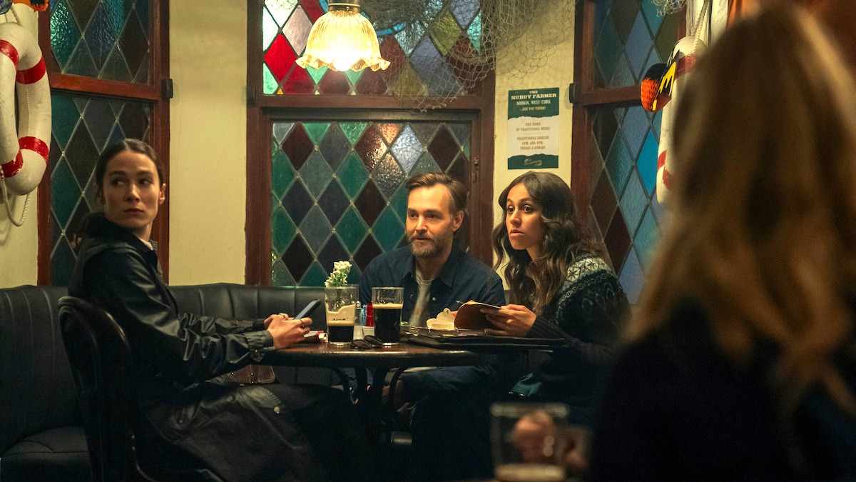 Siobhán Cullen as Dove, Will Forte as Gilbert Power, and Robyn Cara as Emmy sat at a table in Netflix's Bodkin.