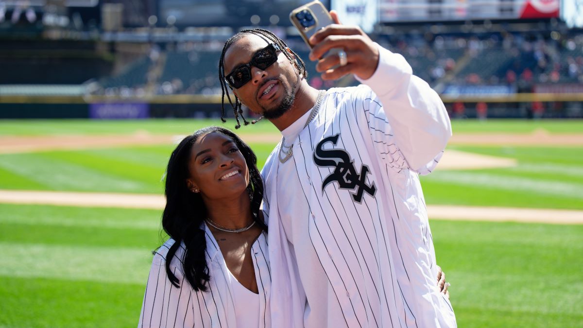Gymnast Simone Biles and Jonathan Owens of the Chicago Bears record a video on the field before Owens threw out a first pitch before a game between the Cincinnati Reds and the Chicago White Sox at Guaranteed Rate Field on April 13, 2024 in Chicago, Illinois. (Photo by Jamie Sabau/Getty Images)
