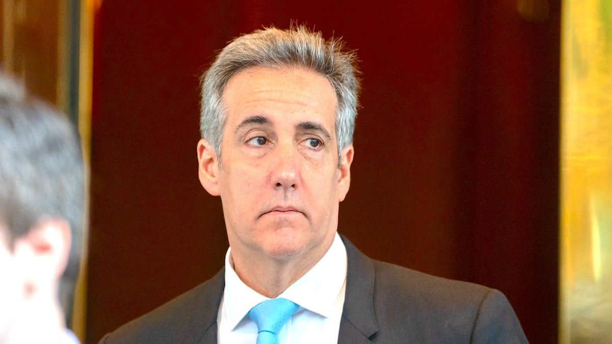 Michael Cohen wearing a gray suit and baby blue tie and looking to his left