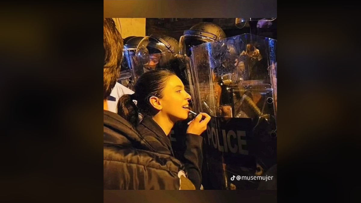 The viral photo of a girl fixing her lip gloss in a police riot shield.