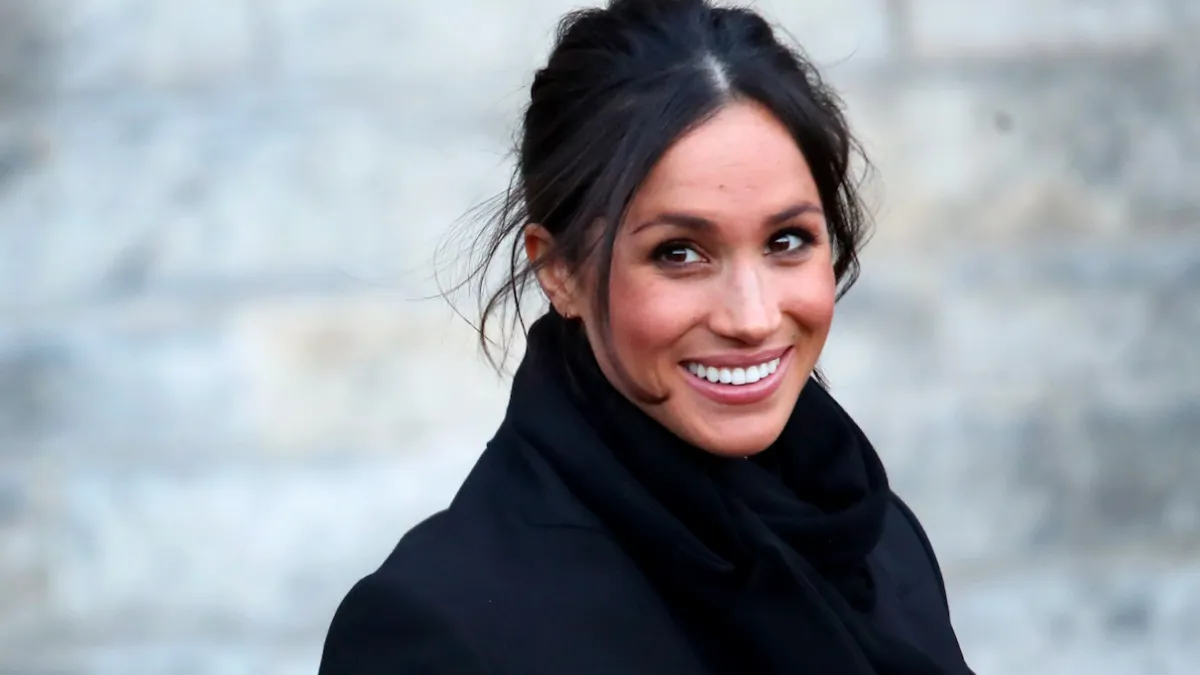 eghan Markle departs from a walkabout at Cardiff Castle wearing a fuzzy black coat.