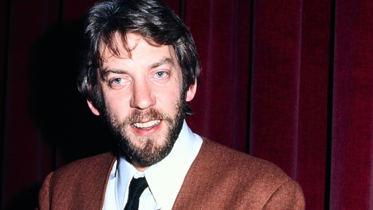 Canadian actor Donald Sutherland, wearing a brown blazer over a white shirt with a black tie, holding documents and newspaper, United States, March 1971.