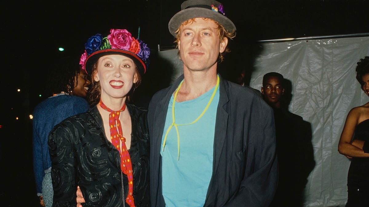 American actress Shelley Duvall, wearing a black jacket with a red neckerchief with multi-coloured polka dots and a floral trimmed hat, and American singer, songwriter and musician Dan Gilroy, who wears a black jacket over a turquoise blue t-shirt with a grey hat.