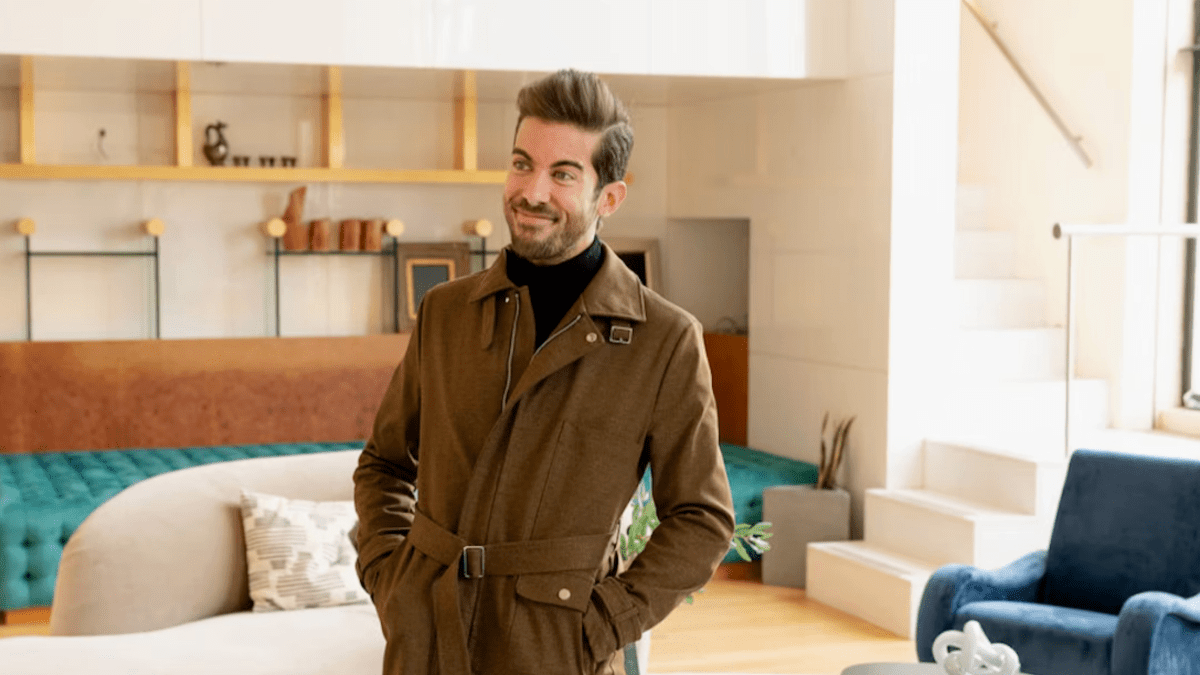 Luis D. Ortiz of Bravo's 'Million Dollar Listing New York' is wearing a dapper coat and standing in a furnished room.