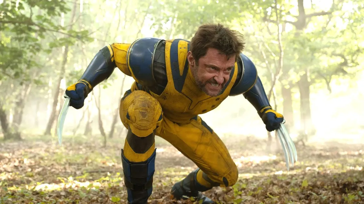 Hugh Jackman's Logan crouches with his claws unleashed in a woodland area in Deadpool & Wolverine