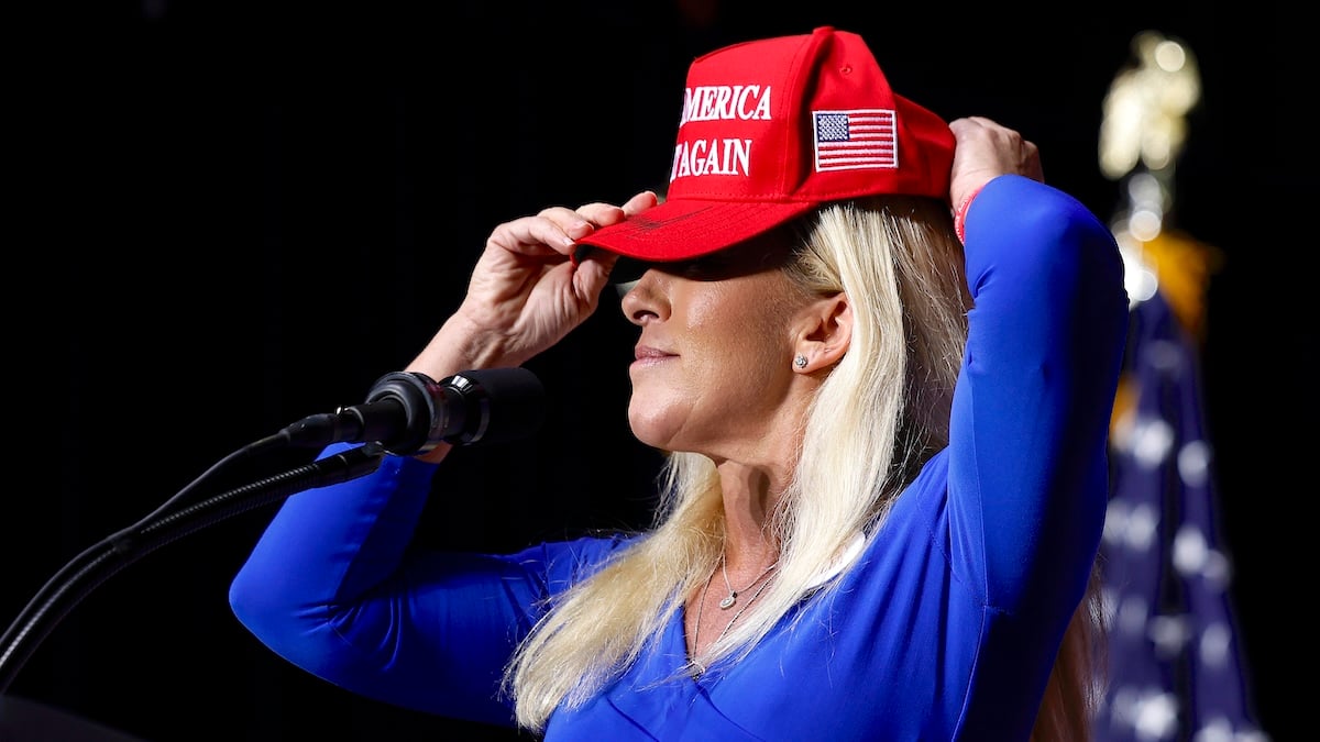 Rep. Marjorie Taylor Greene (R-GA) puts on her Make America Great Again hat while addressing a campaign rally